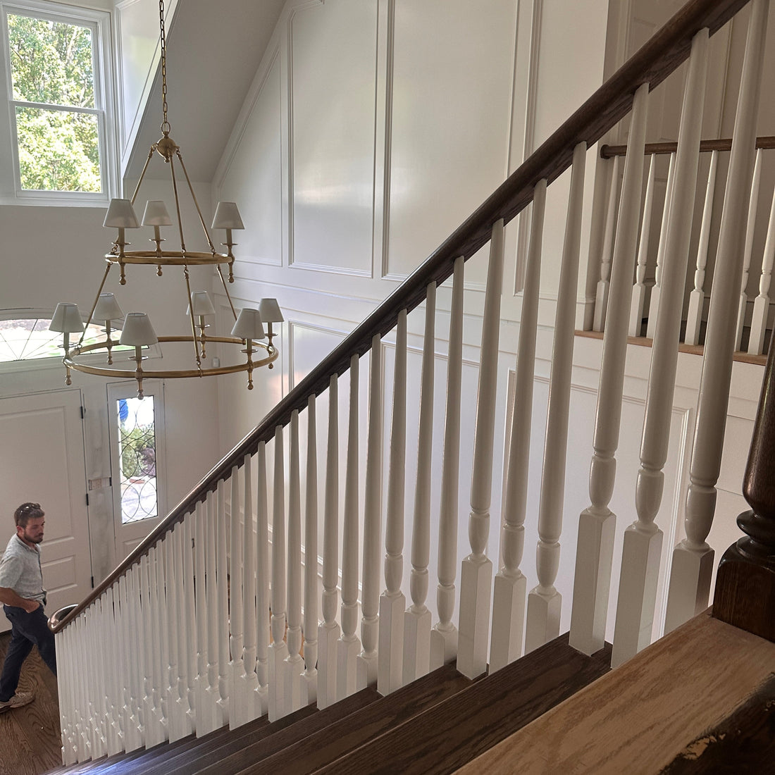 Finished custom staircase in Atlanta with white turned balusters, dark red oak handrail, and a brass chandelier in the entry