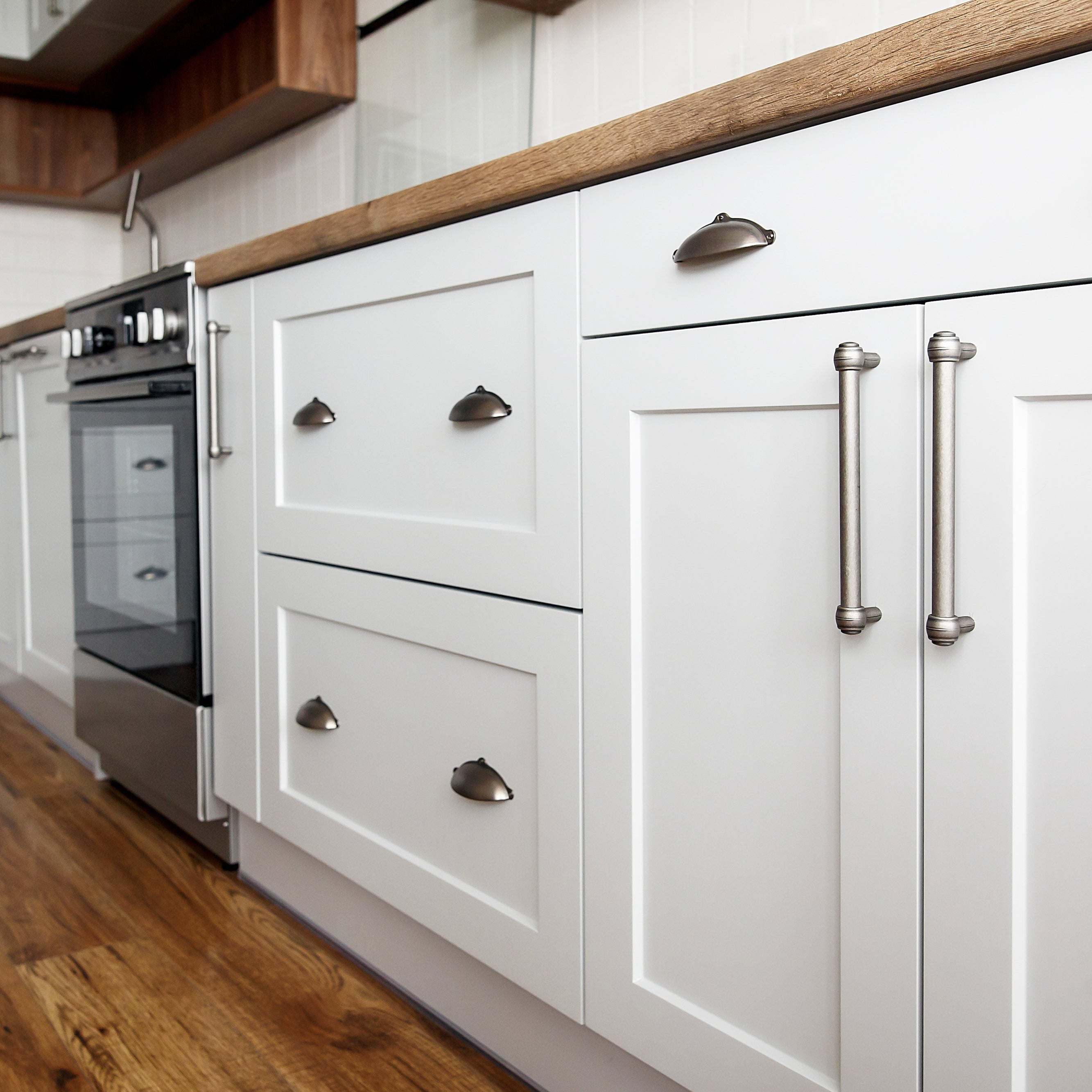 Modern kitchen with white cabinets, wooden countertops, and stainless steel appliances.