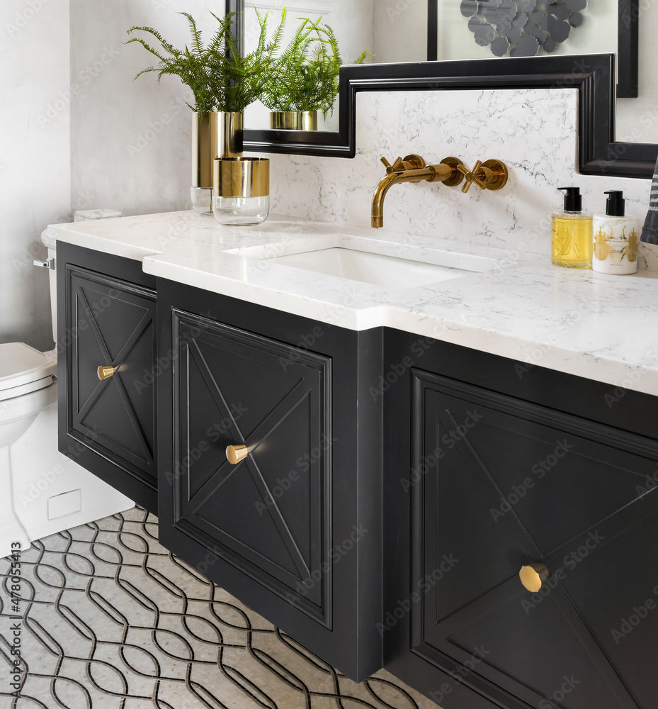 Bathroom vanity with black cabinets, gold fixtures, and decorative elements.