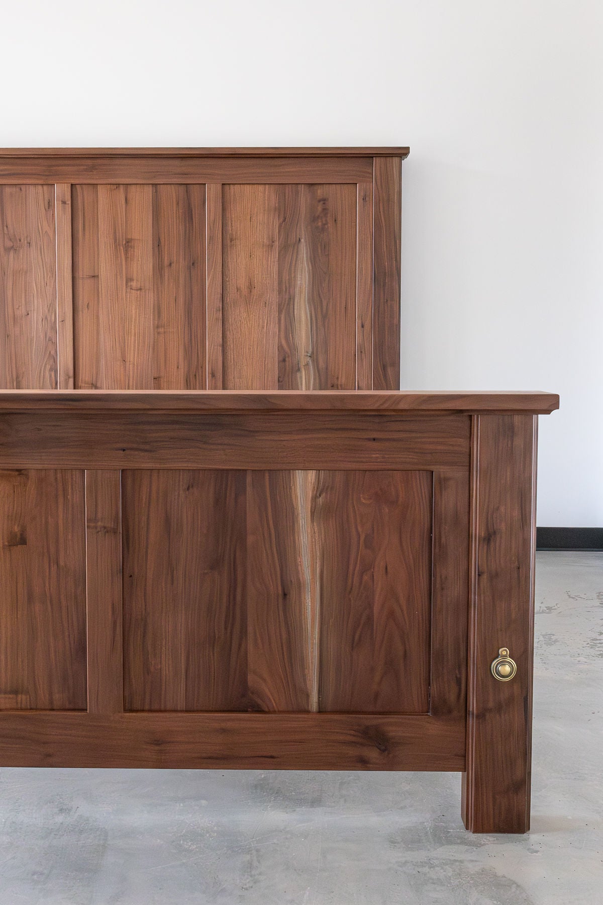 King-sized air-dried black walnut bed with frame and panel construction and vertical grain flowing from footboard to headboard