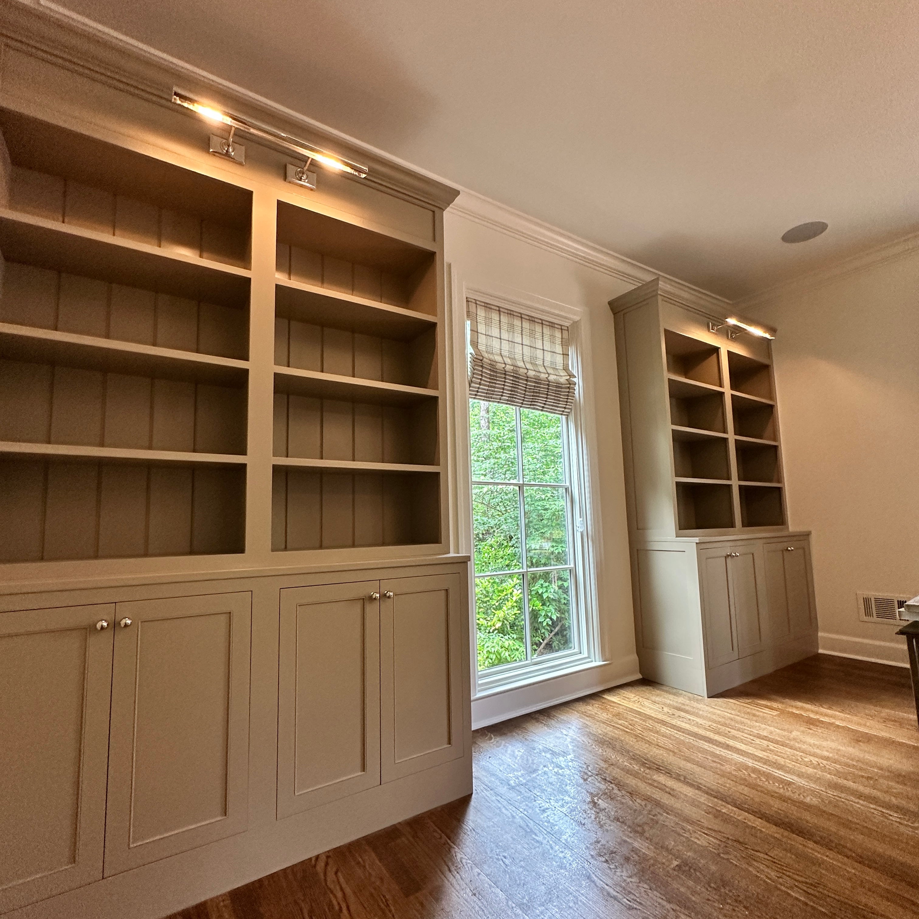 Large V Groove panel built-in bookshelves in a room with a window and wooden floor.